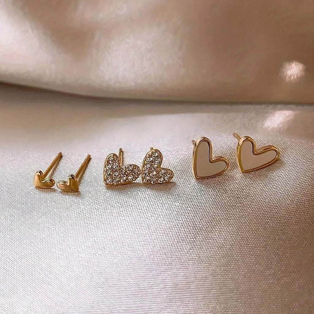 Three pairs of heart shape alloy earrings in gold, black, black white, and pink colours with love design elements