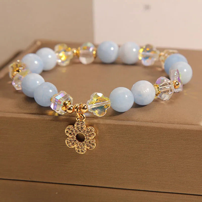 Women's adjustable bracelet with aquamarine crystal four-leaf clover charm and pearl detail.