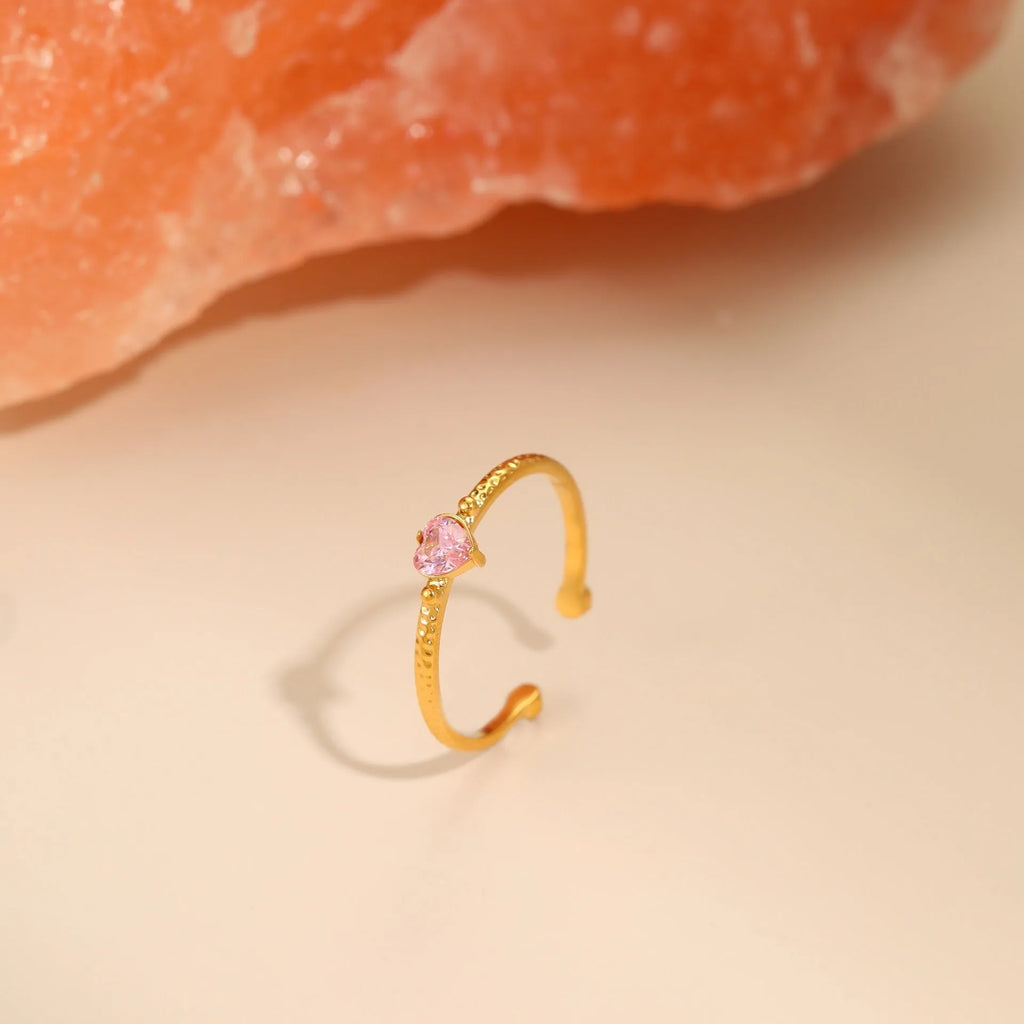 Open-ended adjustable ring with heart-shaped zircon decoration in geometric styling, shown in three colour variations.