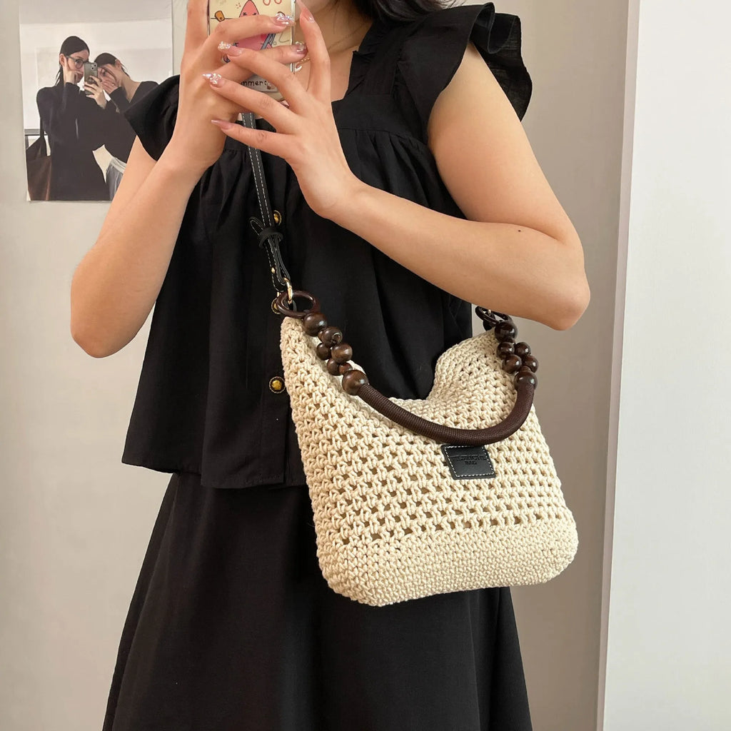 Black knitted bucket tote bag with contrast stitching showing internal zipper compartment