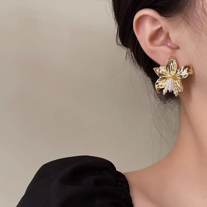 Gold H1795 pearl flower earrings with floral design on a white background.