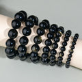 Hand-woven round obsidian bracelet in black stone, shown on a wrist.