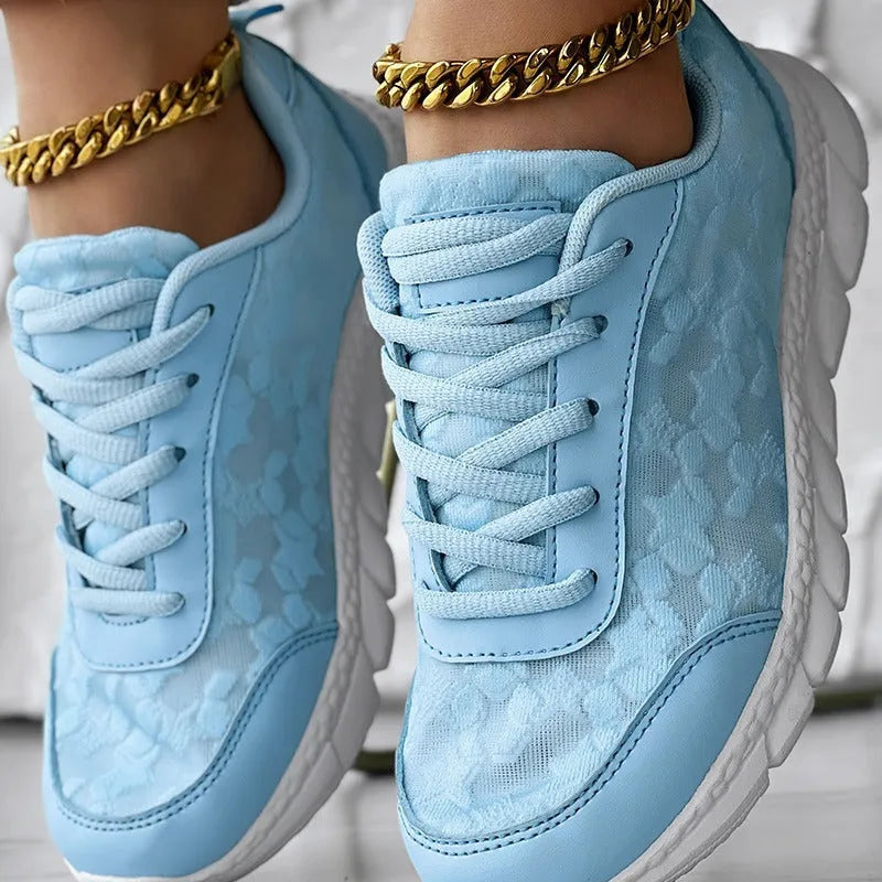Women's white canvas sports shoes with flat heel and round toe on a plain background.
