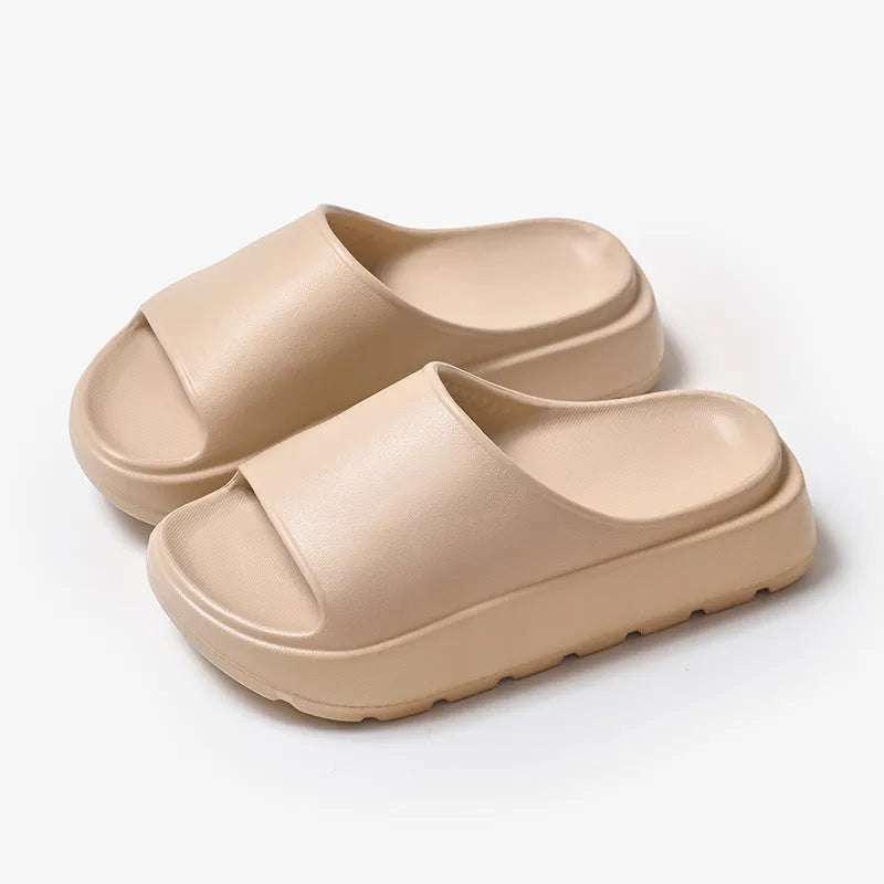 Women's thick-soled EVA beach slippers in beige, shown from the side on a sandy surface.
