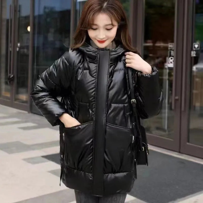 Women's green thick loose fit hooded winter jacket with long sleeves on a hanger.
