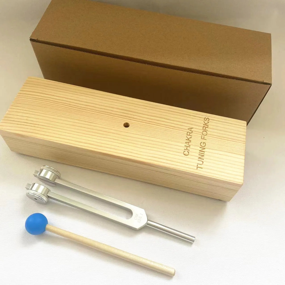 Aluminium alloy 432 Hz tuning fork with built-in speaker on kraft paper box.