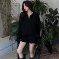 Women's creamy-white knitted suit set with geometric cable pattern, long sleeve sweater, and elastic waist shorts