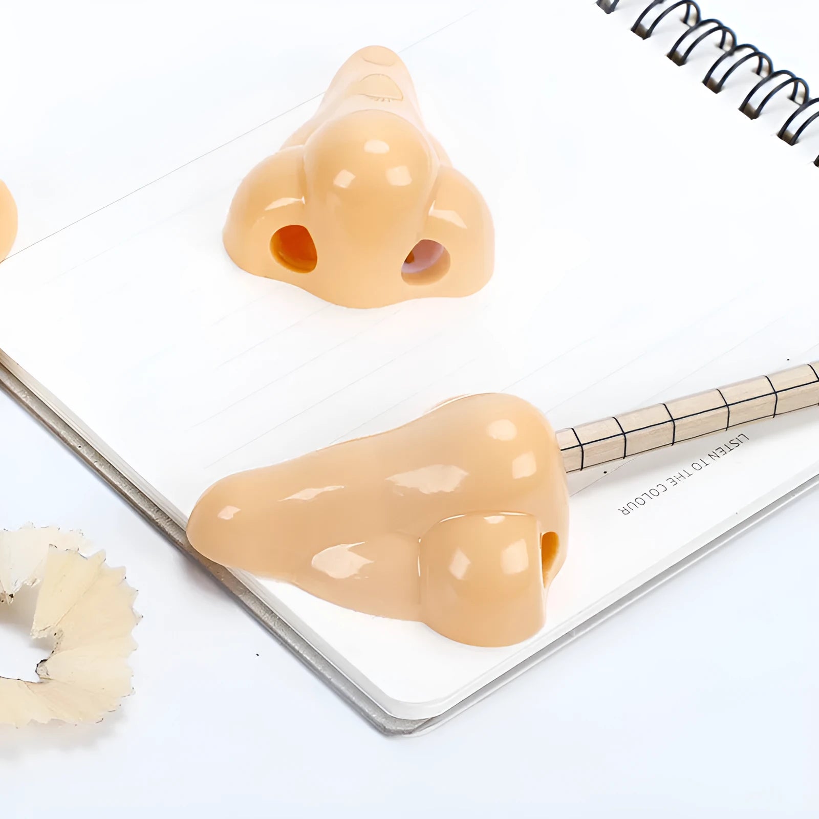 Flesh coloured plastic manual pencil sharpener with a geometry shape and large nostril opening.