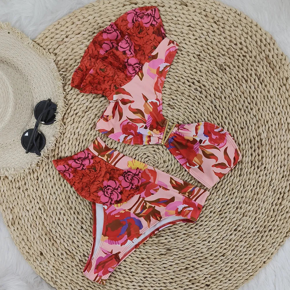 Women's pink floral print one-shoulder ruffled swimsuit with high-waisted bikini briefs.