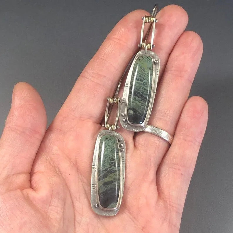 Close-up of simple geometric drop earrings with a two-colour marble pattern finish.
