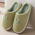 Women's plaid design artificial fur winter slippers with rubber sole on a wooden floor.