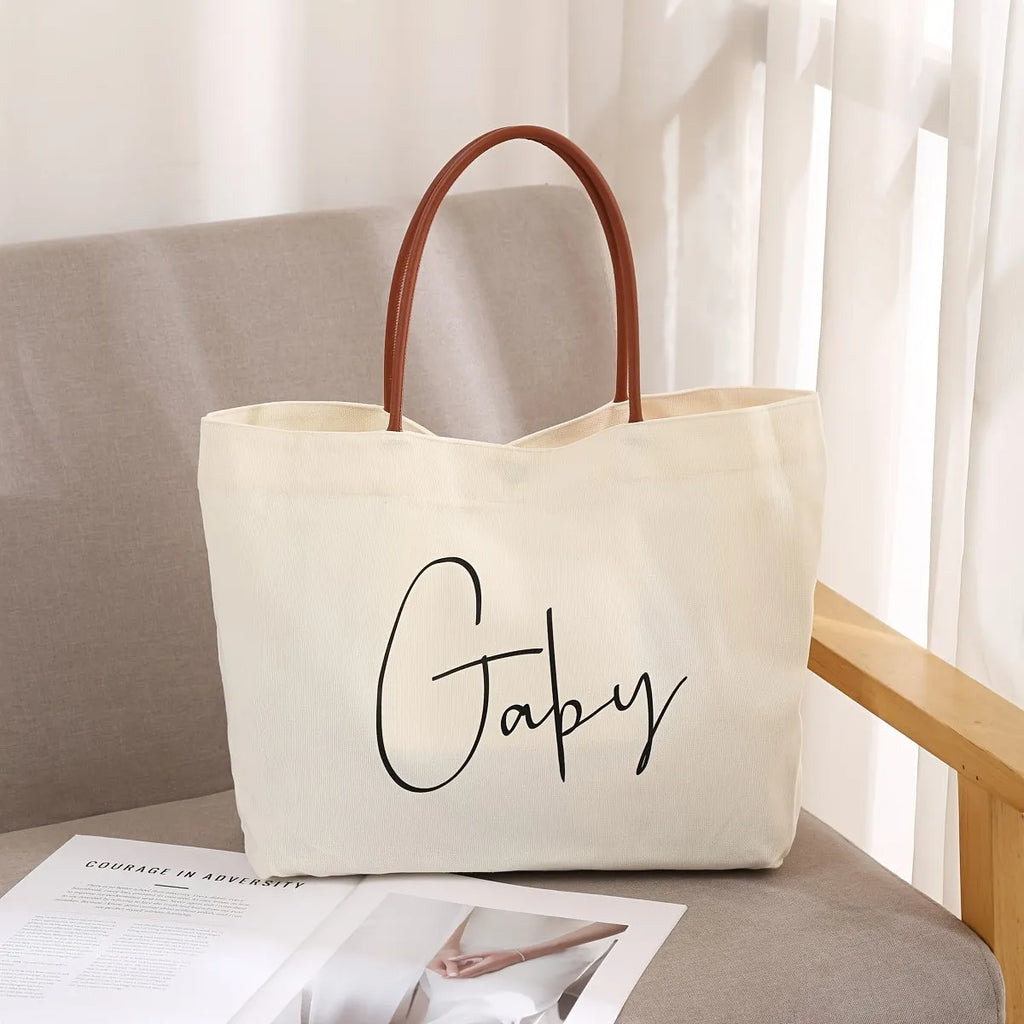 Beige white and white canvas tote bag with long handle straps.