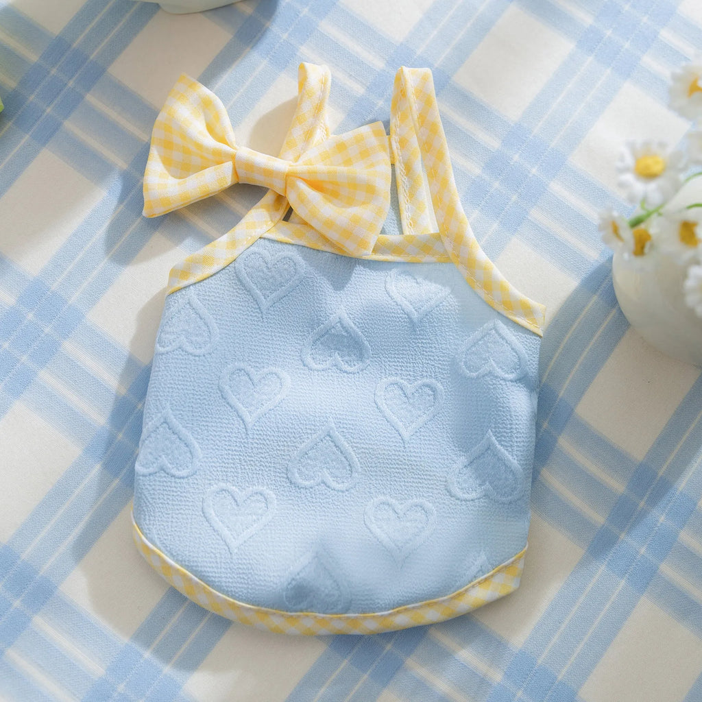 Small dog wearing a blue heart texture vest with bow suspenders and matching hairband