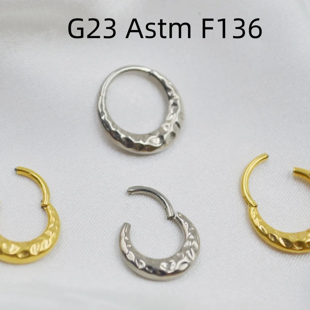 Close-up of a concave-convex carved titanium nose ring in gold and silver finishes.