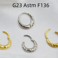 Close-up of a concave-convex carved titanium nose ring in gold and silver finishes.