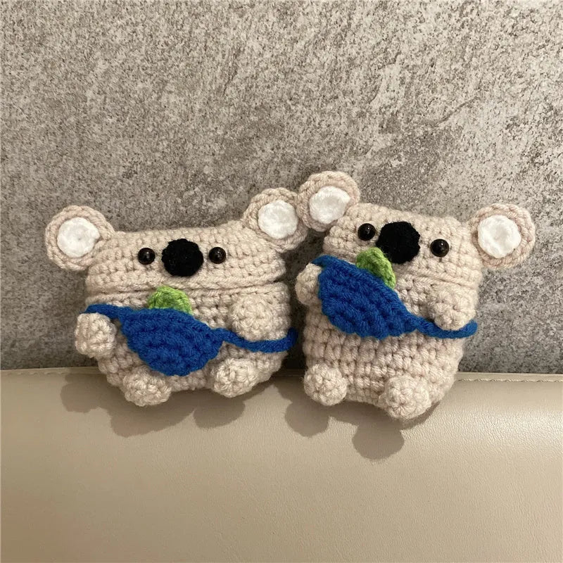 Handmade knitted koala bear backpack cover for AirPods charging case on a table.