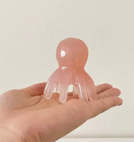 Pink natural resin octopus-shaped massage comb with storage bag.