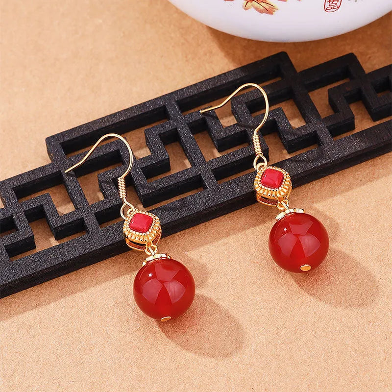 Geometric drop earrings with red agate beads, silver settings, and jasper accents on copper alloy