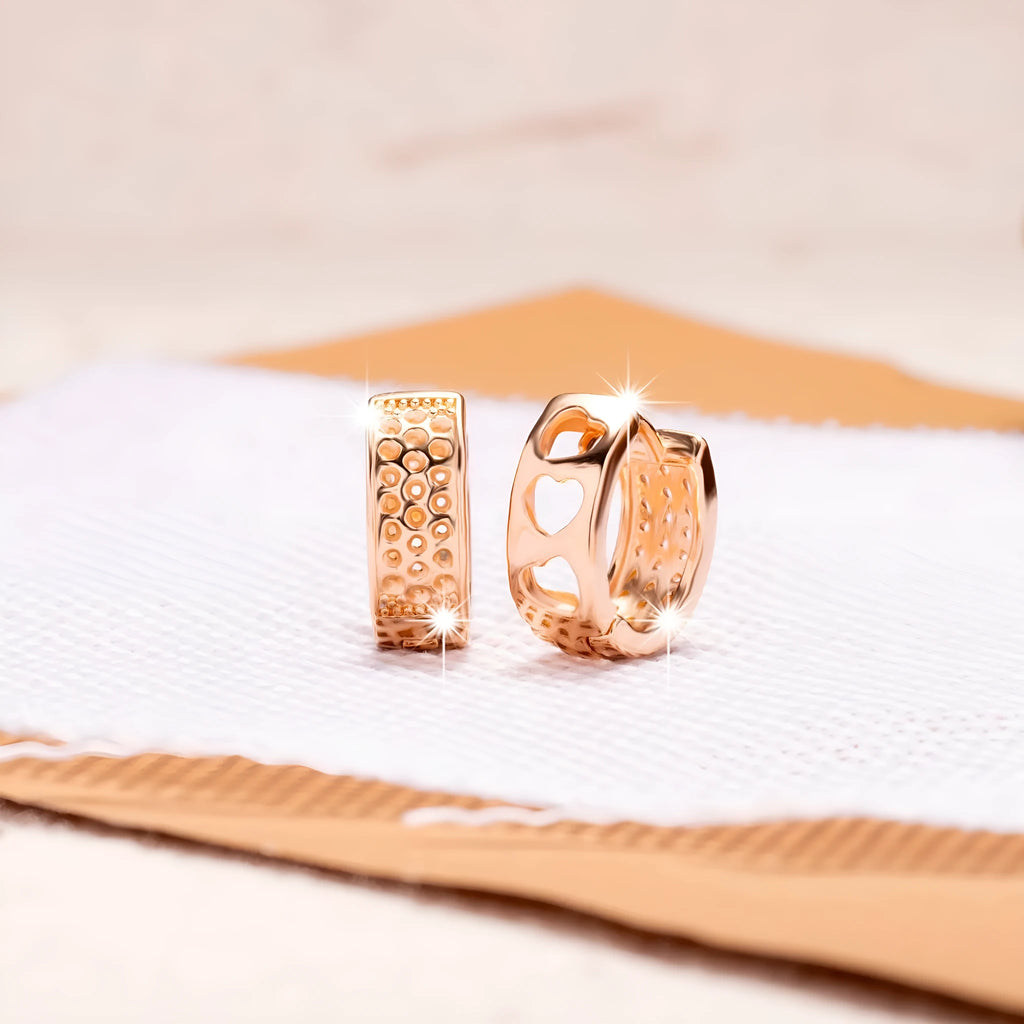 Rose gold coloured circular earrings with a hollowed-out three-heart design.