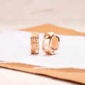 Rose gold coloured circular earrings with a hollowed-out three-heart design.