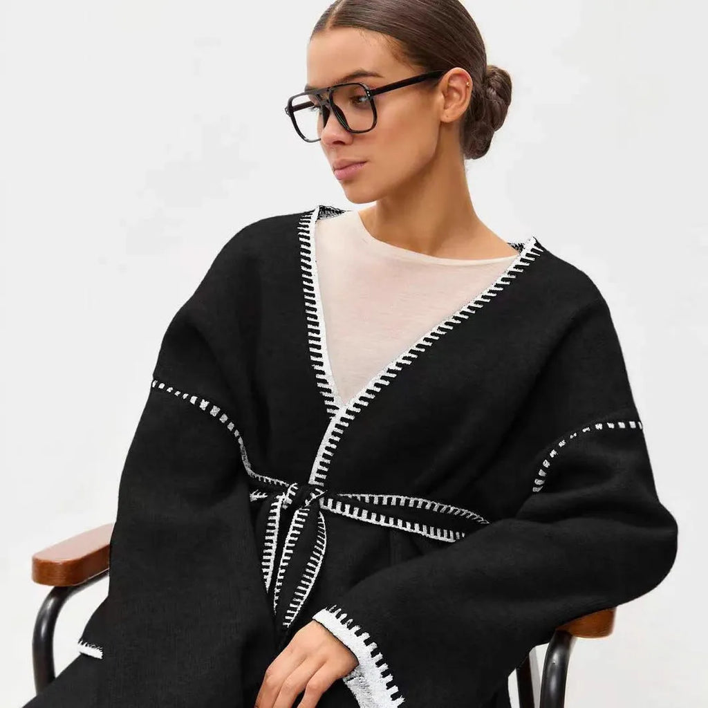 Loose grey knitted cardigan with lace-up front ties on a hanger.