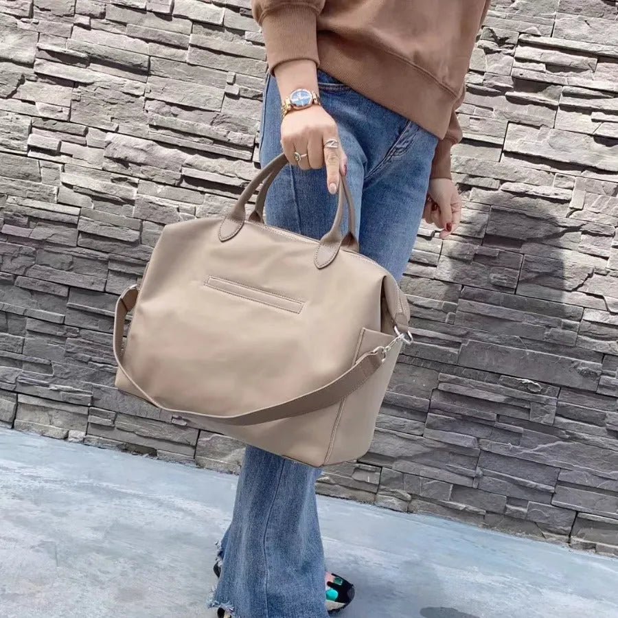 Black nylon waterproof shoulder bag with leather handbag detail and large main compartment.