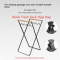 Black outdoor folding iron trash rack with wooden handle holding a rubbish bag.