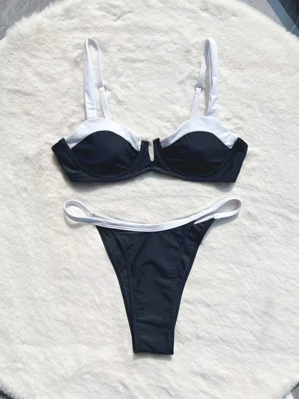 Black low waist women's bikini swimsuit with stitching split detail on a mannequin.