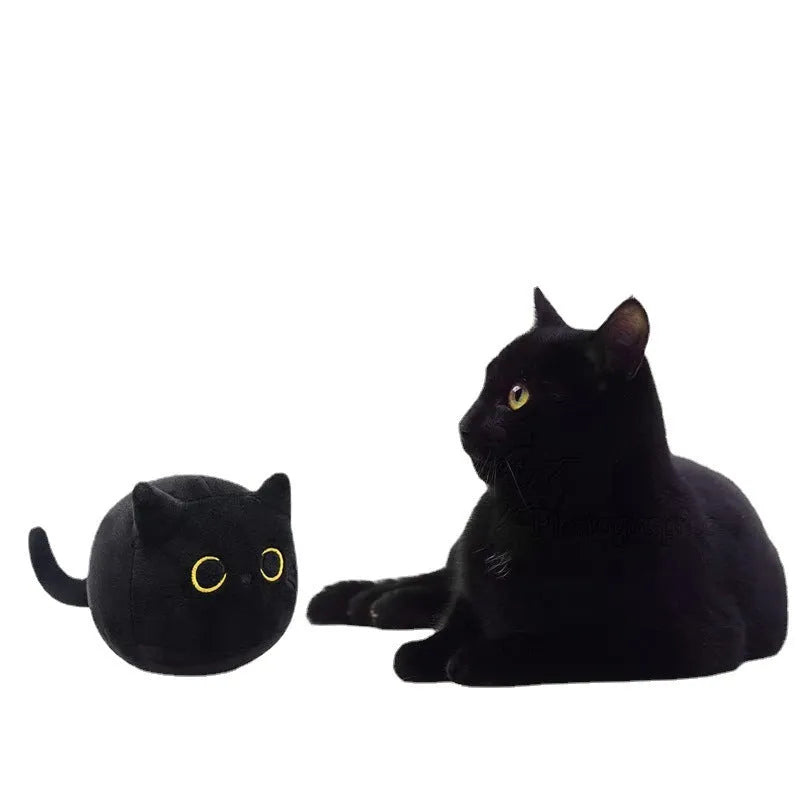 Fluffy black cat plush toy used as a soft pillow cushion on a sofa.