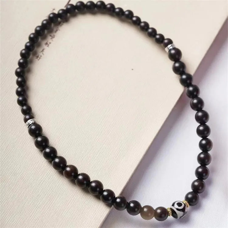 Dark ebony wood bracelet with 8mm beads in a two-circle Tibetan style on a wrist.