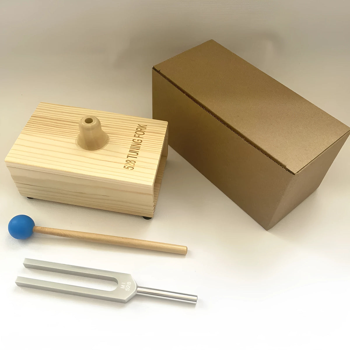 Aluminium alloy 432 Hz tuning fork with built-in speaker on kraft paper box.