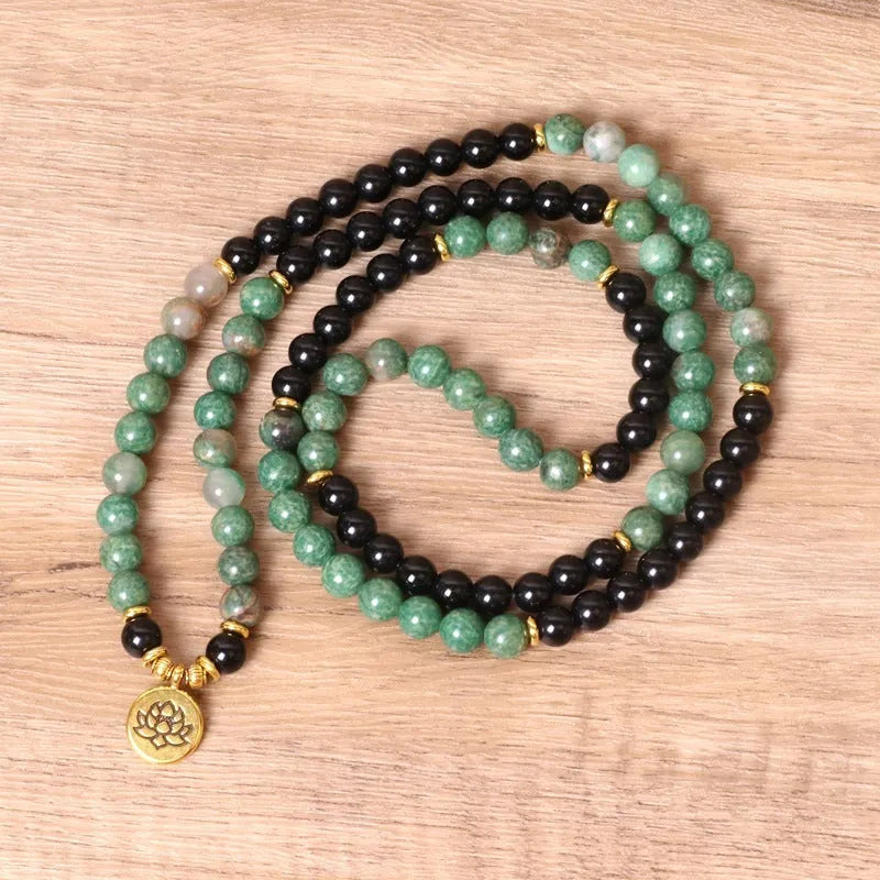 Green and black alloy bead elastic bracelet stretched on a wrist.