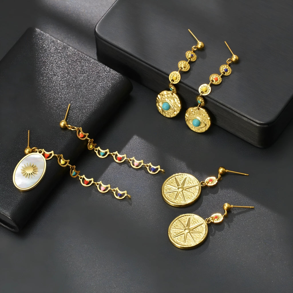 Geometric stainless steel earrings showing eight-avn star, eye, and shell sun designs