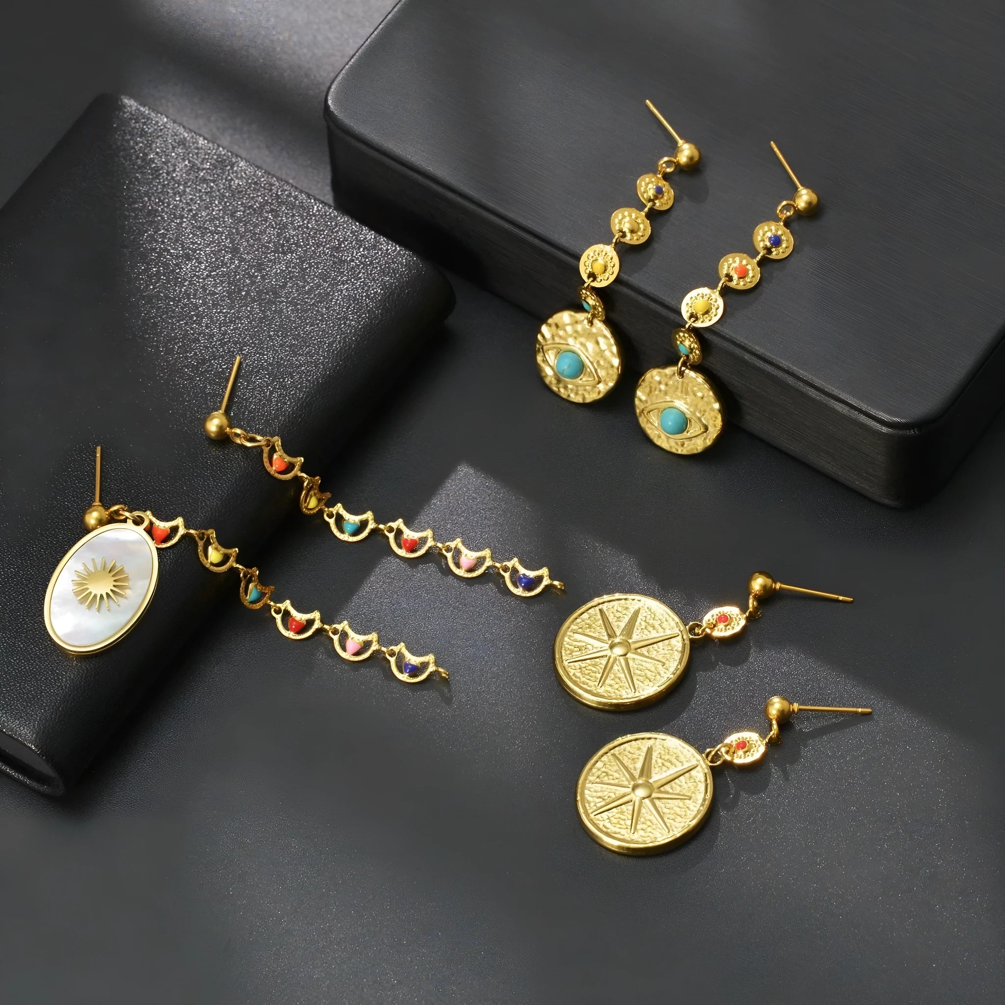 Geometric stainless steel earrings showing eight-avn star, eye, and shell sun designs