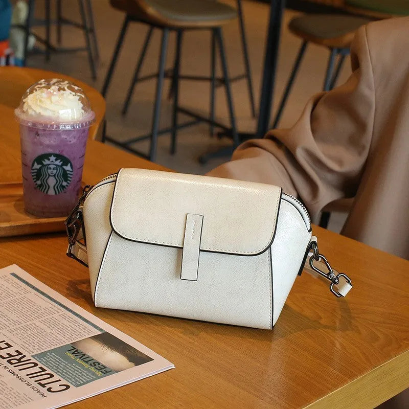 Brown women's genuine leather messenger bag with cross-body strap, showing outer sandwich pocket and visible sewing detail.