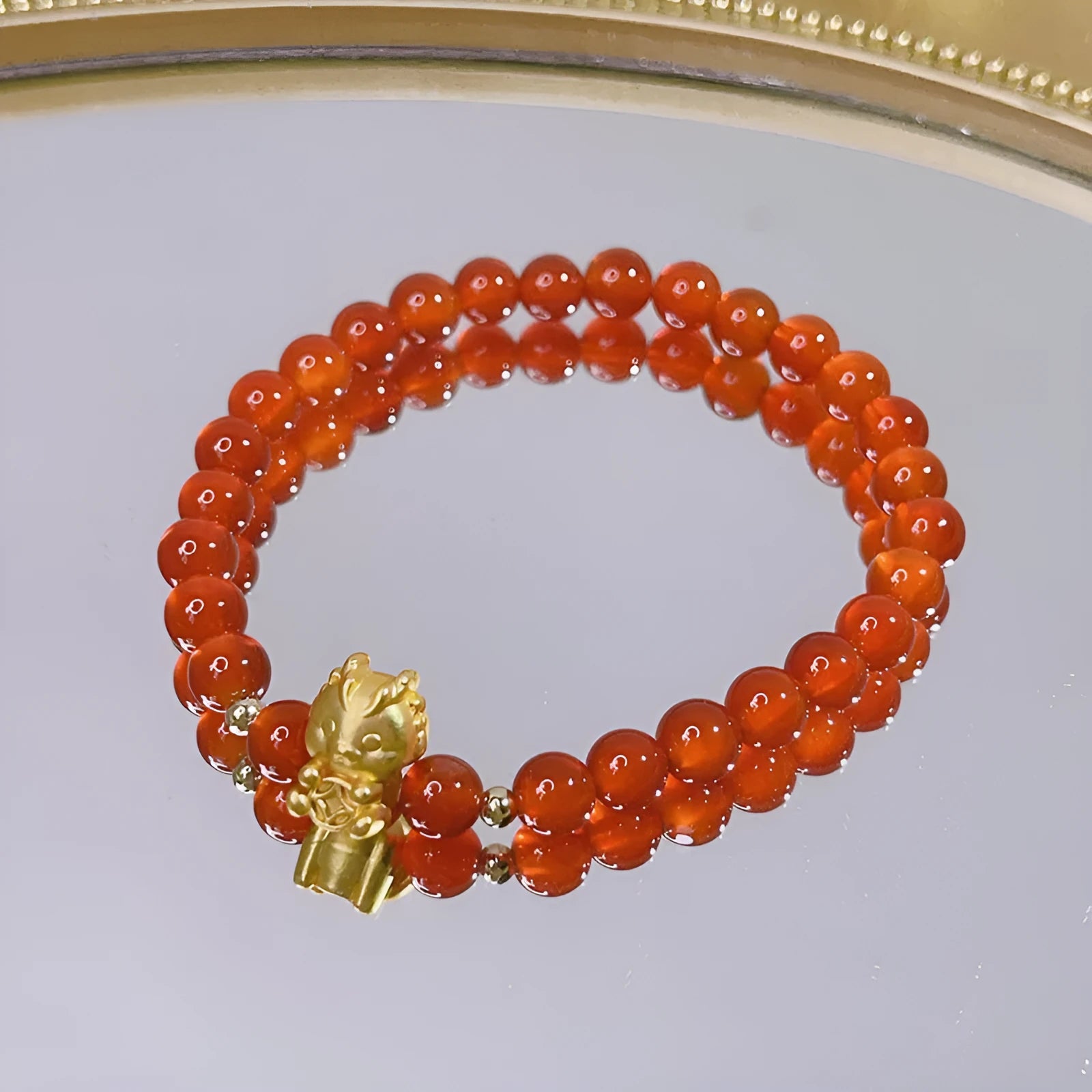 Close-up of a manually crafted red agate bracelet with Lucky Bag and dragon designs on a wrist.
