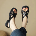 Glossy black patent leather women's sandals with a square toe and cross strap design.