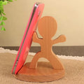 Solid beech wood mobile phone stand with a coin slot, shown alongside resin novelty designs including a dog and elephant holder.