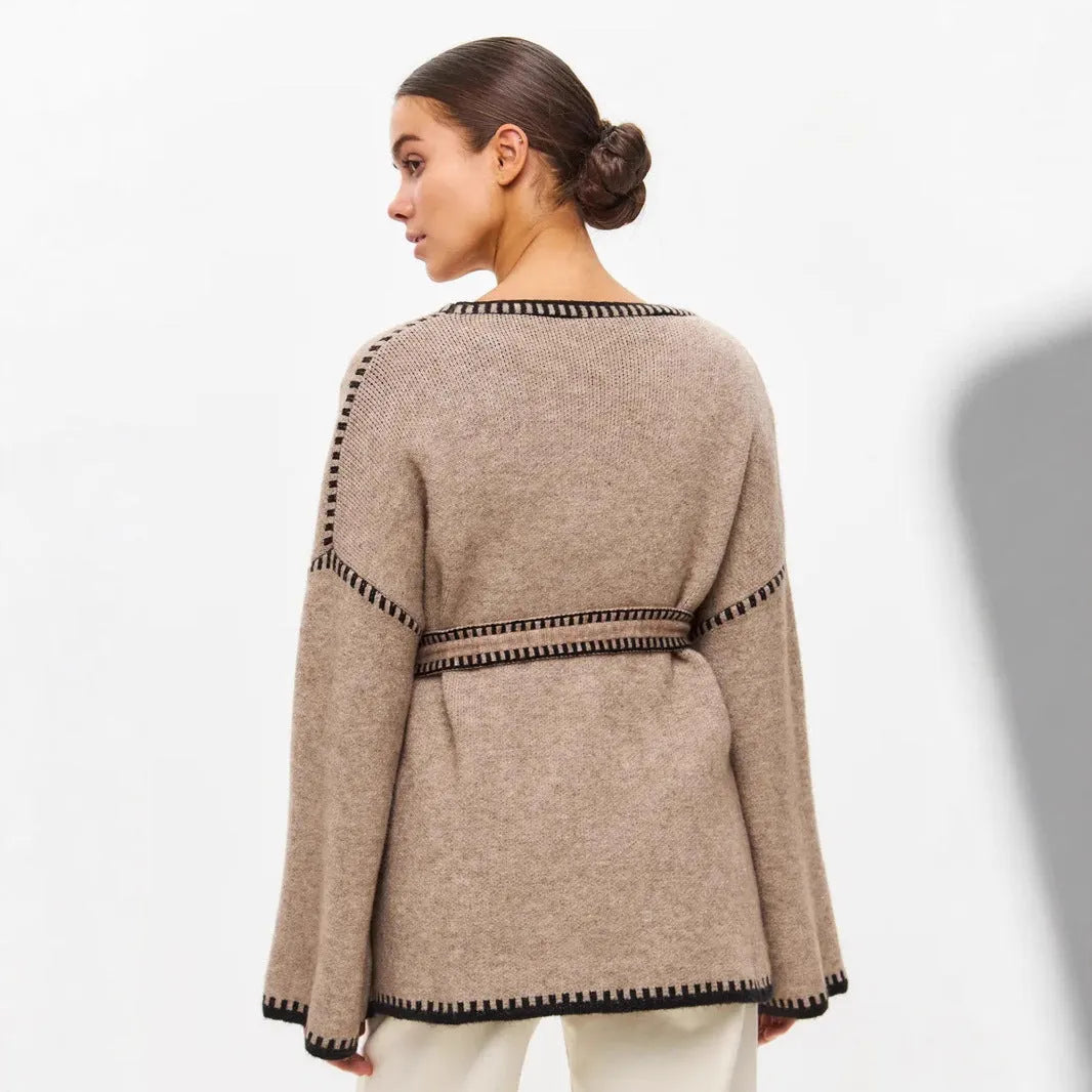 Loose grey knitted cardigan with lace-up front ties on a hanger.
