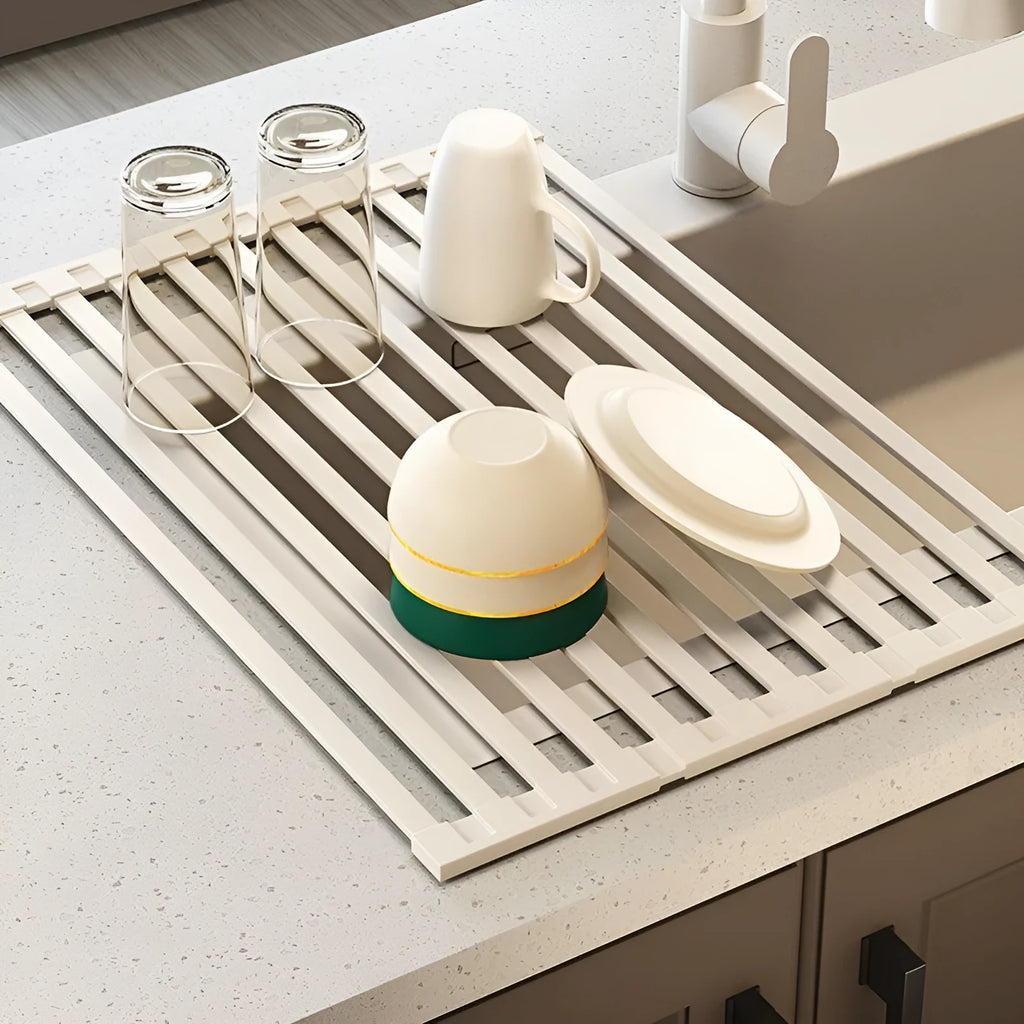 Milky white foldable stainless steel kitchen draining rack shown unfolded next to a sink.