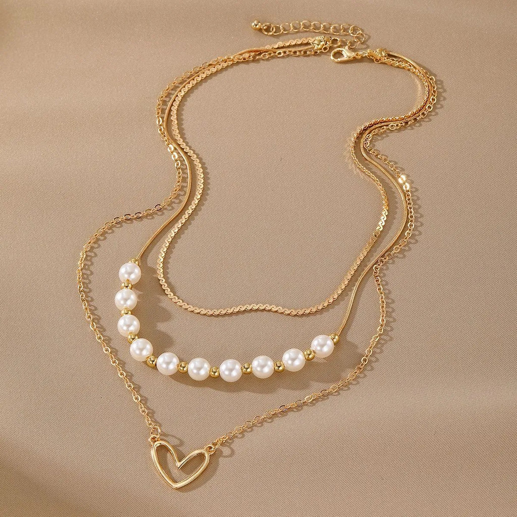 Vintage gold necklace with love heart pendant on a pearl chain, adjustable length.
