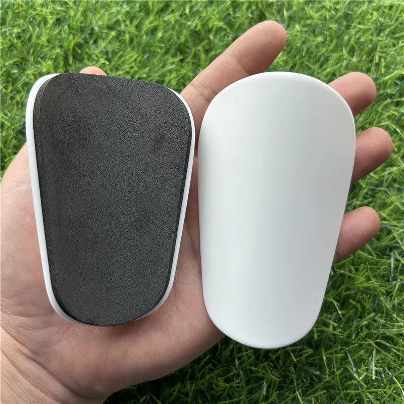 Extra small plastic football shin guards in black and white, measuring 8x5cm