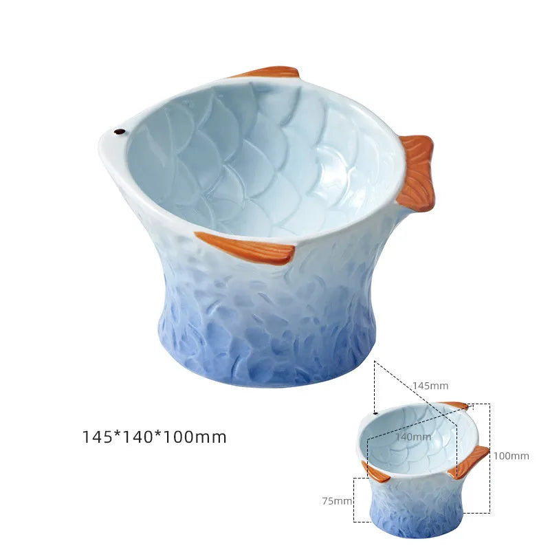 Four coloured fish-shaped ceramic cat bowls with tilted bases on a table.