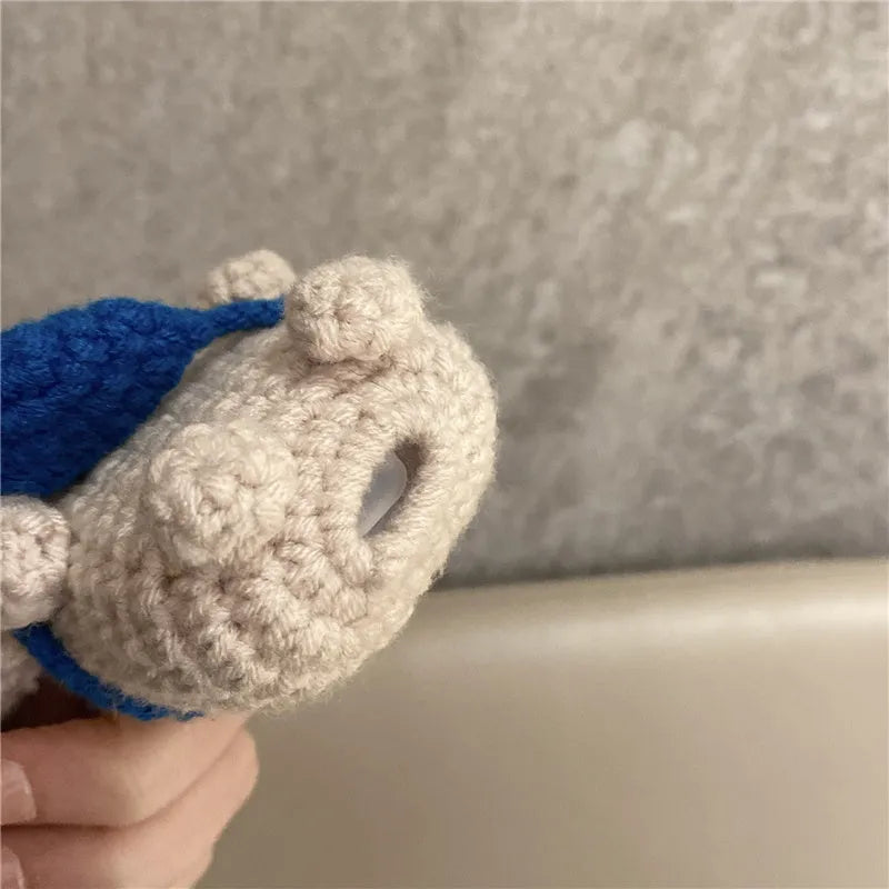 Handmade knitted koala bear backpack cover for AirPods charging case on a table.