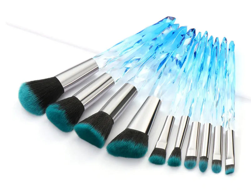 Ten clear crystal-handled foundation brushes with artificial fibre bristles, laid out in a set.