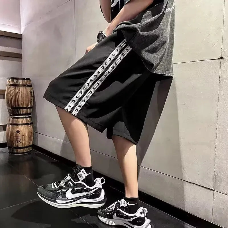 Men's loose-fit black track pants with an elasticated waist, shown on a hanger.
