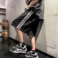 Men's loose-fit black track pants with an elasticated waist, shown on a hanger.