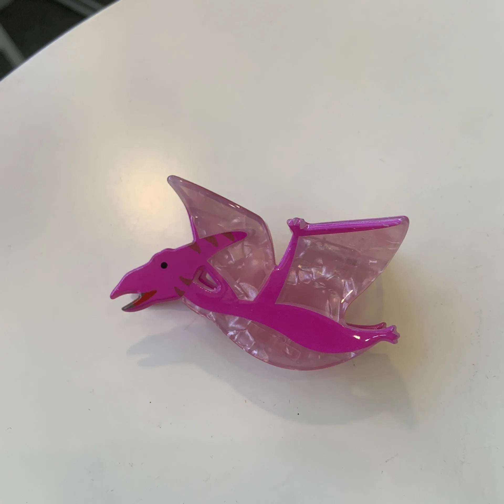 Dinosaur-shaped acrylic jaw clip hair grip in assorted colours including blue, brown, green, pink, and purple.