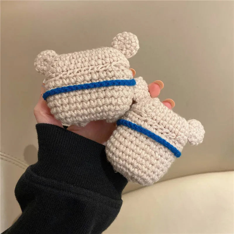 Handmade knitted koala bear backpack cover for AirPods charging case on a table.
