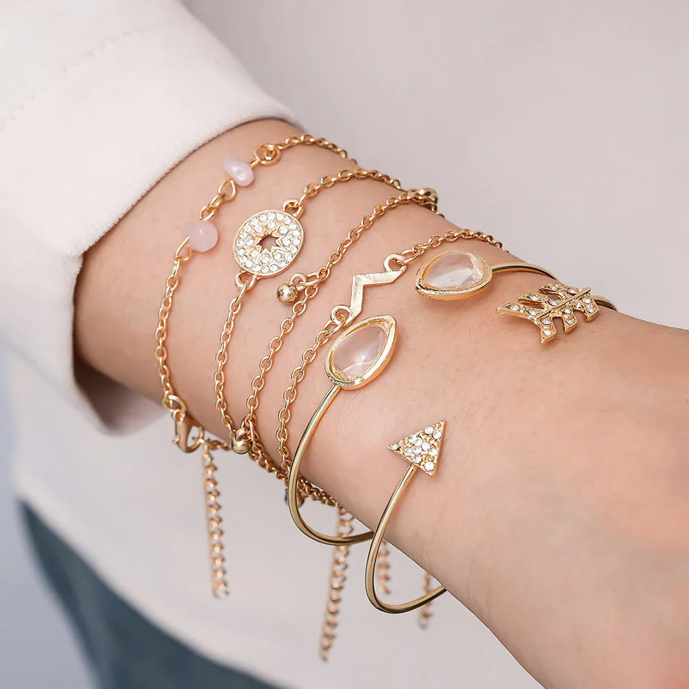 Set of six golden bracelets with arrow, water drop and V shapes featuring spot drill pattern.